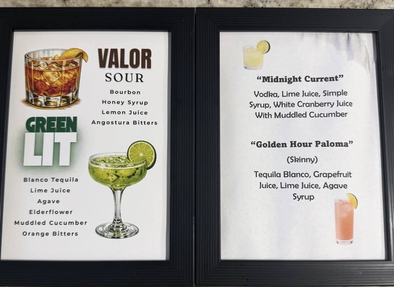 Two framed cocktail menus on a countertop listing Valor Sour, Green LIT, Midnight Current and Golden Hour Paloma